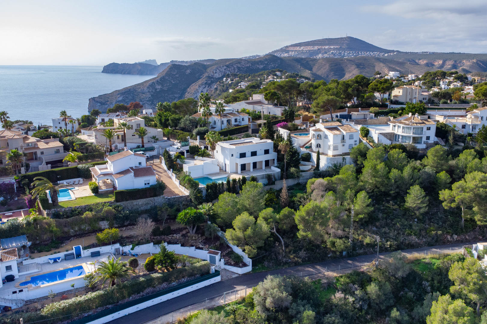 Vue aérienne de la zone résidentielle Granadella-Ambolo, montrant des villas nichées sur la colline avec vue panoramique sur la mer et les falaises.