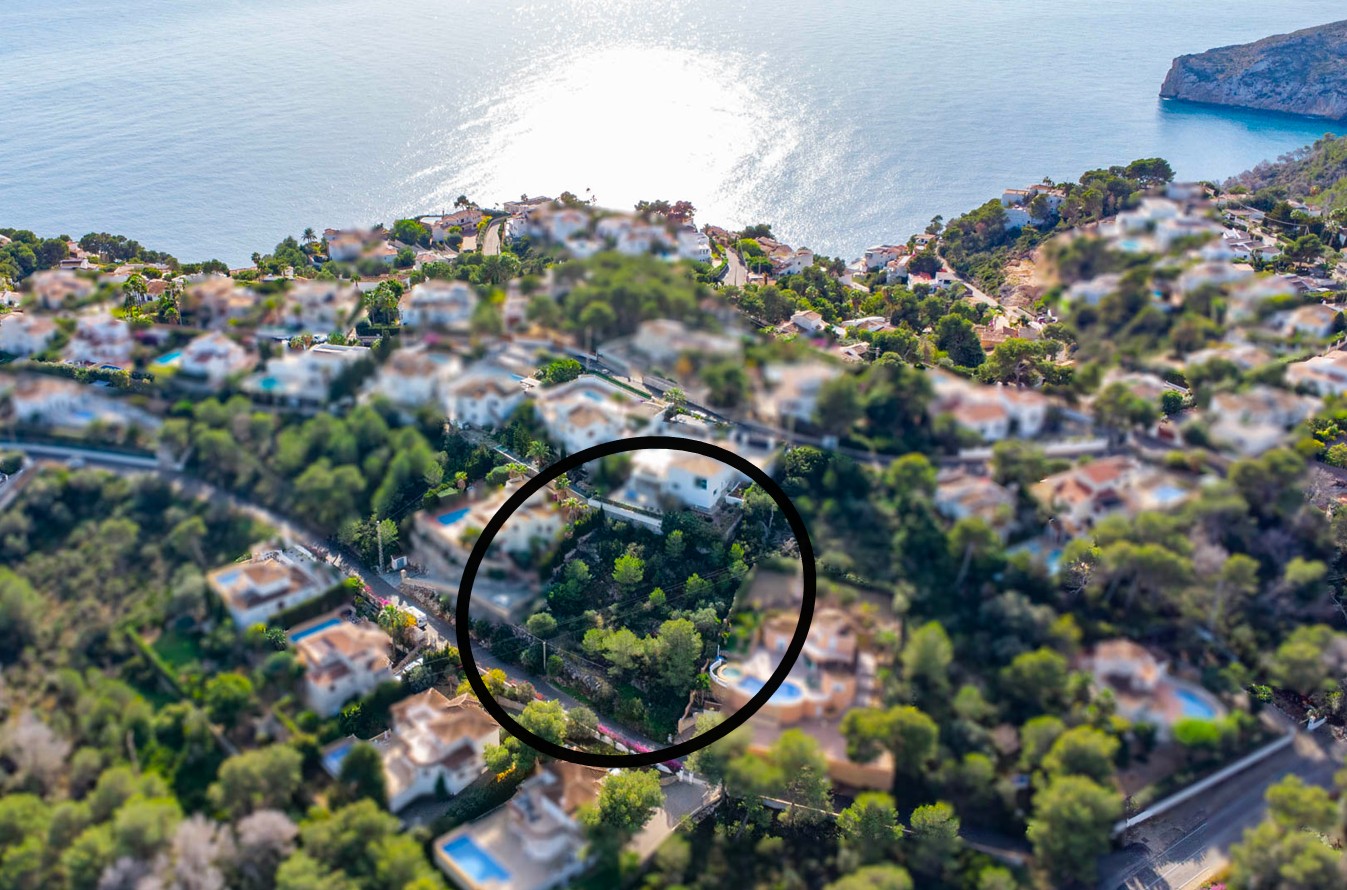 Vue aérienne du terrain à bâtir de 1042m2 entouré de pins, situé sur un versant offrant une vue dégagée sur la mer Méditerranée à Jávea.