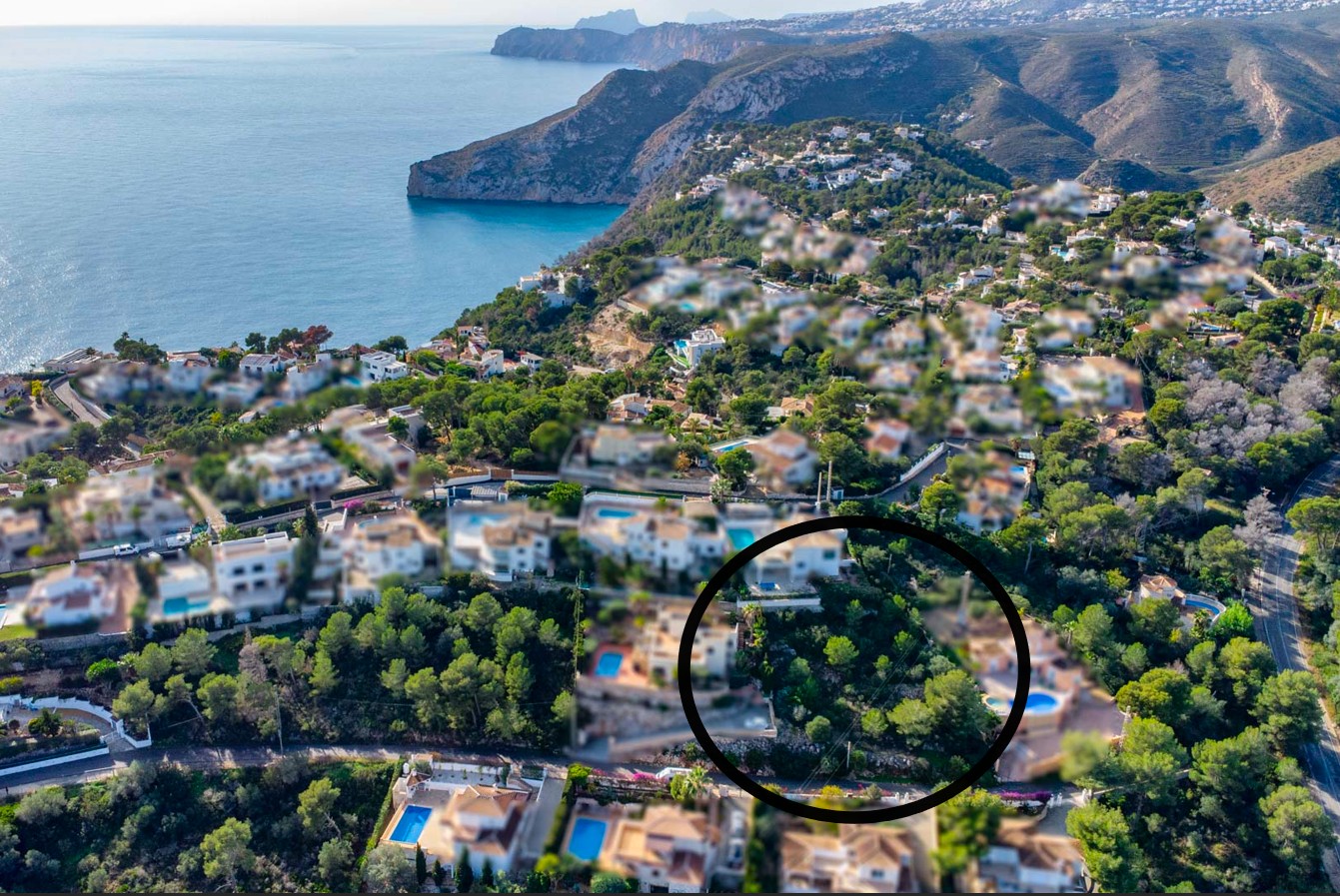 Vue aérienne du terrain de 1042 m² entouré de pins dans le quartier d'Ambolo, offrant une vue dégagée sur la mer Méditerranée et les falaises de Jávea.
