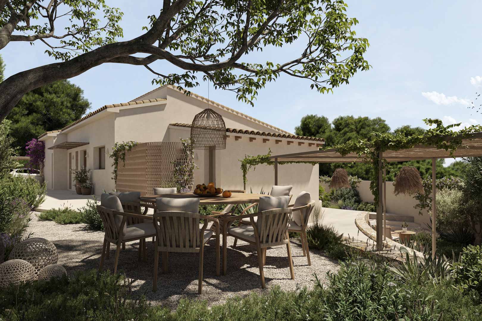 Coin repas extérieur avec table ronde en bois et chaises tressées sur gravier, entouré d'un jardin méditerranéen avec pergola et végétation dense.