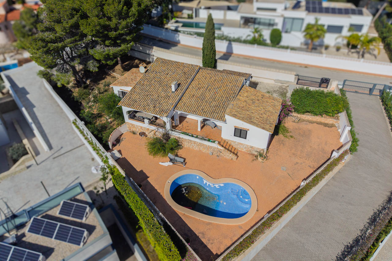 Vue aérienne de la villa illustrant le terrain plat, la piscine de forme organique et l'architecture méditerranéenne avec ses toits en tuiles et ses terrasses.