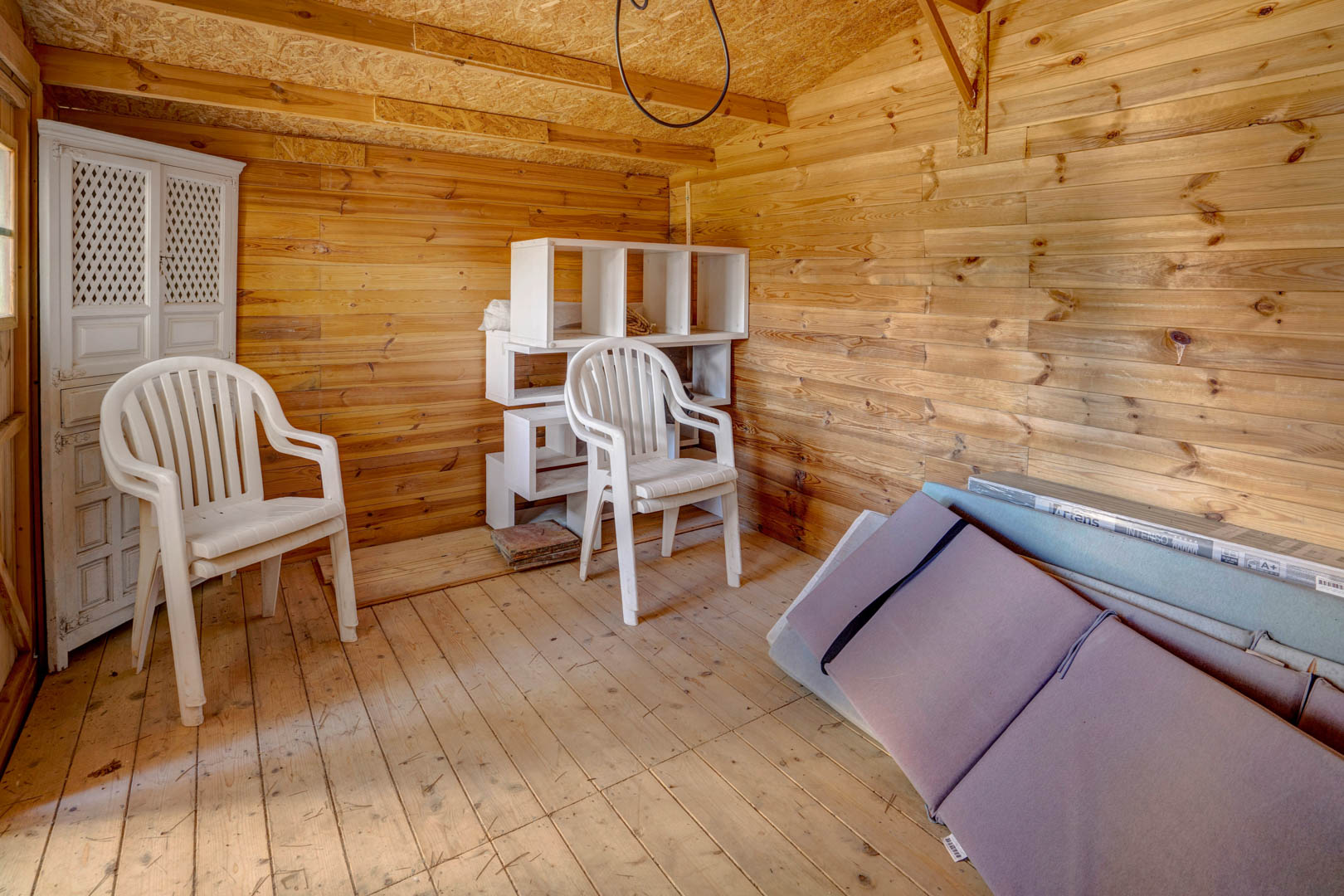Dépendance ou débarras entièrement revêtu de bois, offrant un espace de rangement sain et polyvalent bénéficiant d'un éclairage naturel latéral.