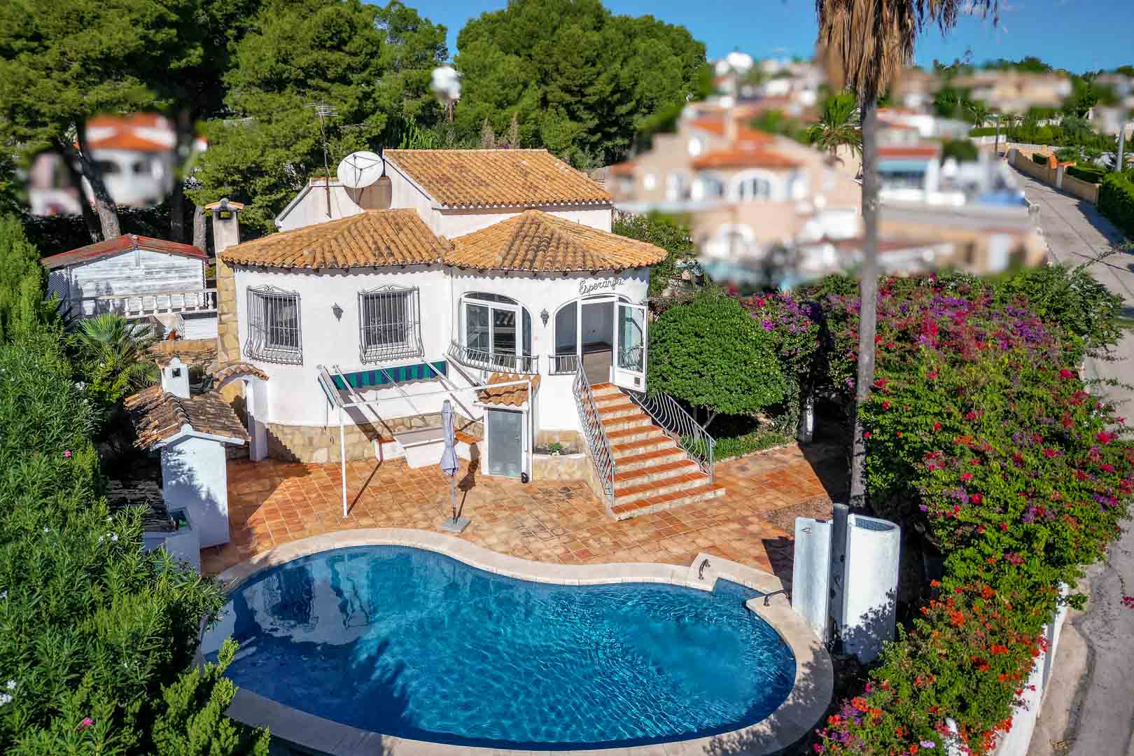 Vue aérienne de la villa avec piscine en forme de rein, terrasse en terre cuite et escalier menant à la véranda vitrée, entourée d'un jardin méditerranéen.