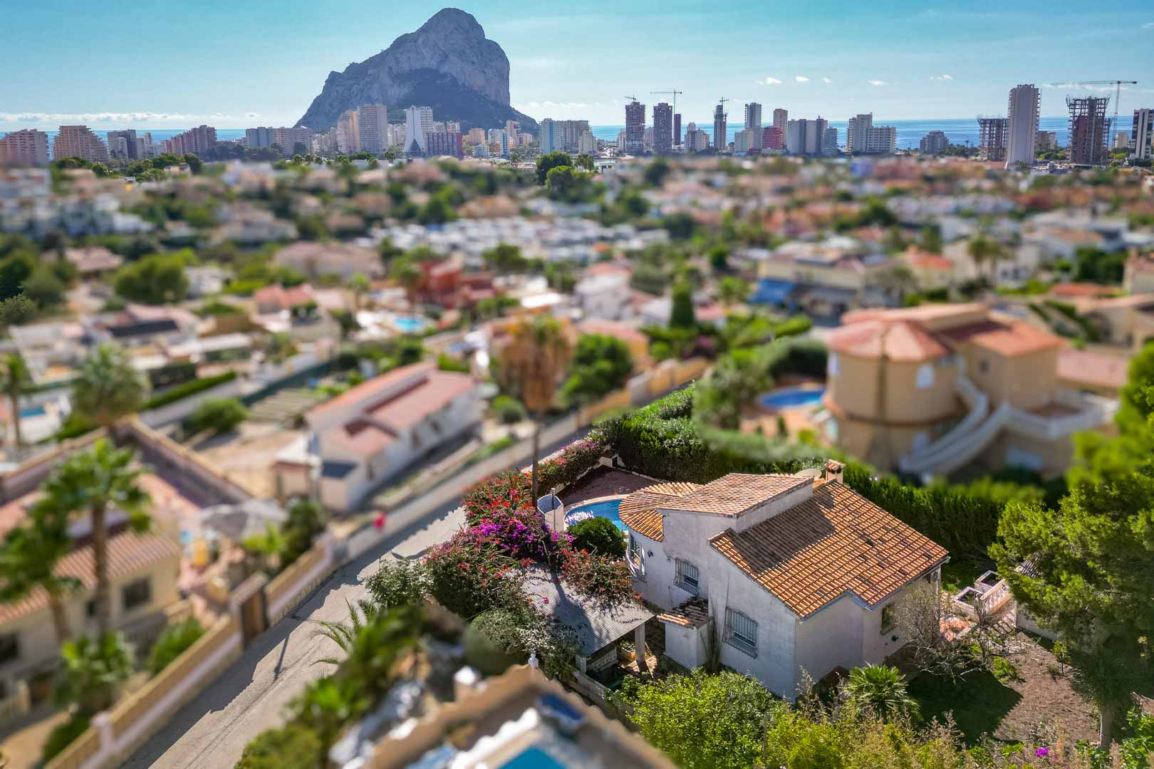 Vue aérienne de la villa avec piscine privée et jardin, offrant un panorama dégagé sur le Peñón de Ifach et l'horizon urbain de Calpe.