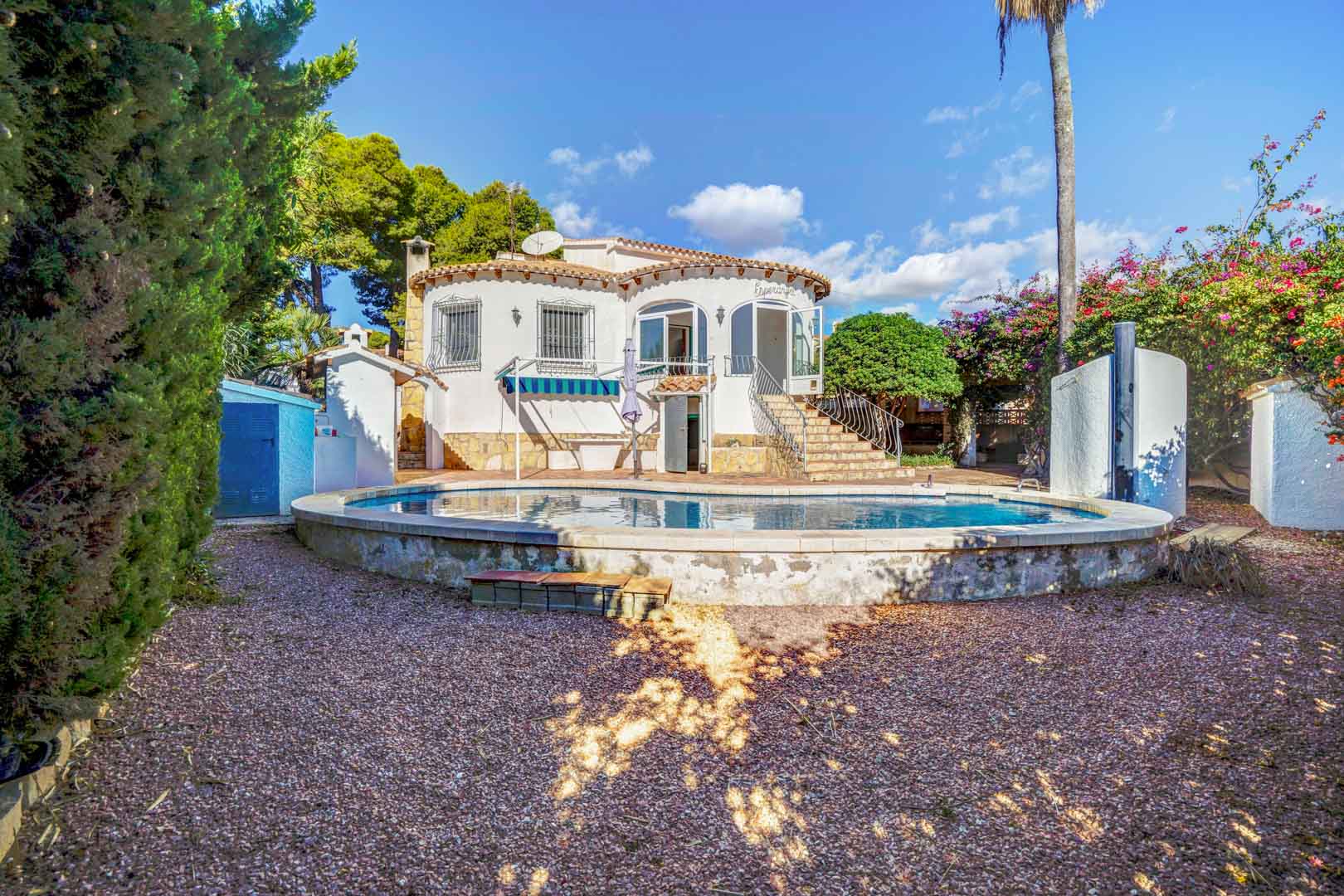 Vue extérieure de la villa avec piscine privée surélevée, jardin de gravier et escaliers en pierre menant à la terrasse vitrée.