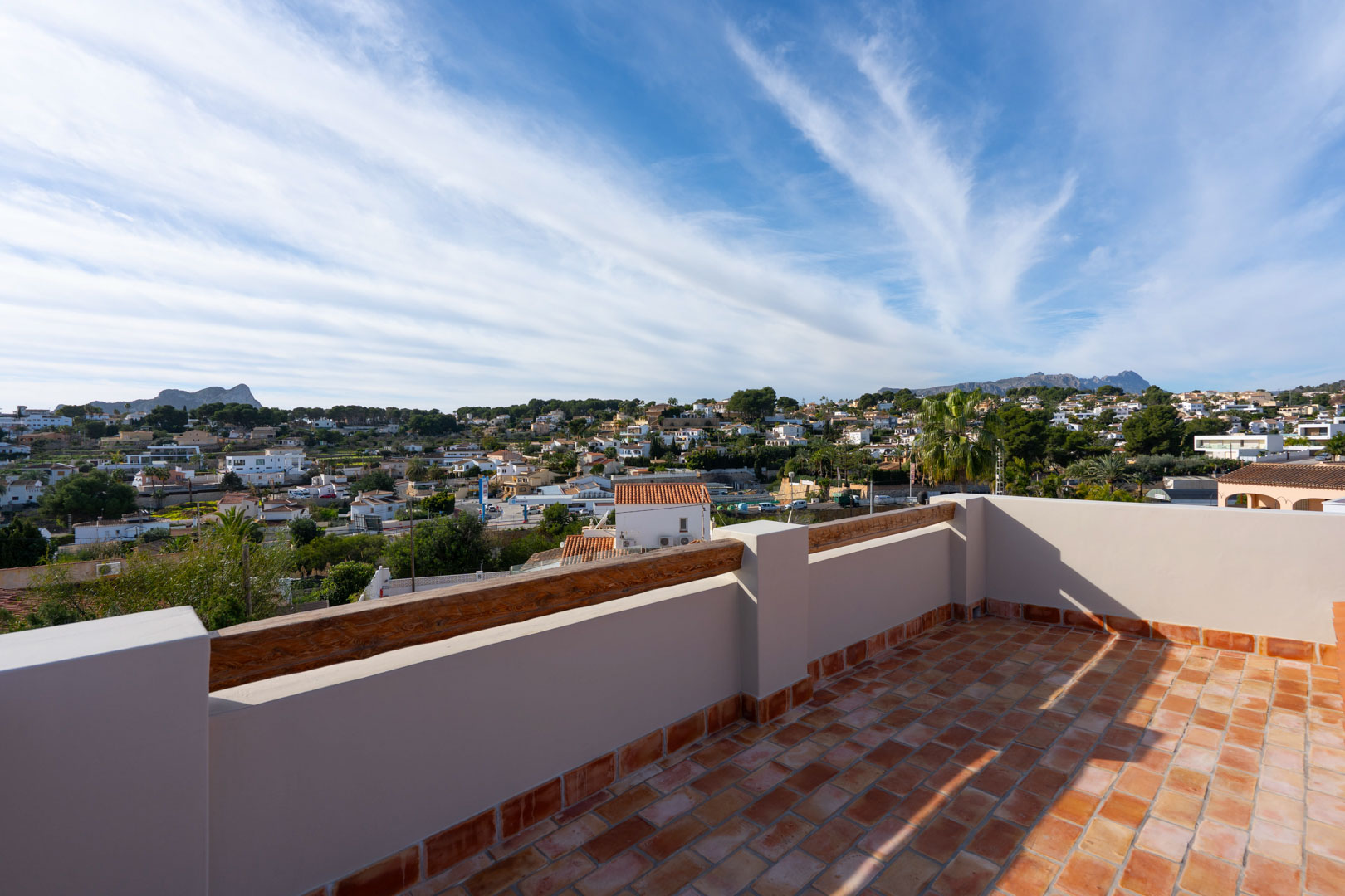 Toit-terrasse avec sol en terre cuite et finitions en bois, offrant une vue panoramique sur le Peñón de Ifach, la Sierra de Bernia et les environs.