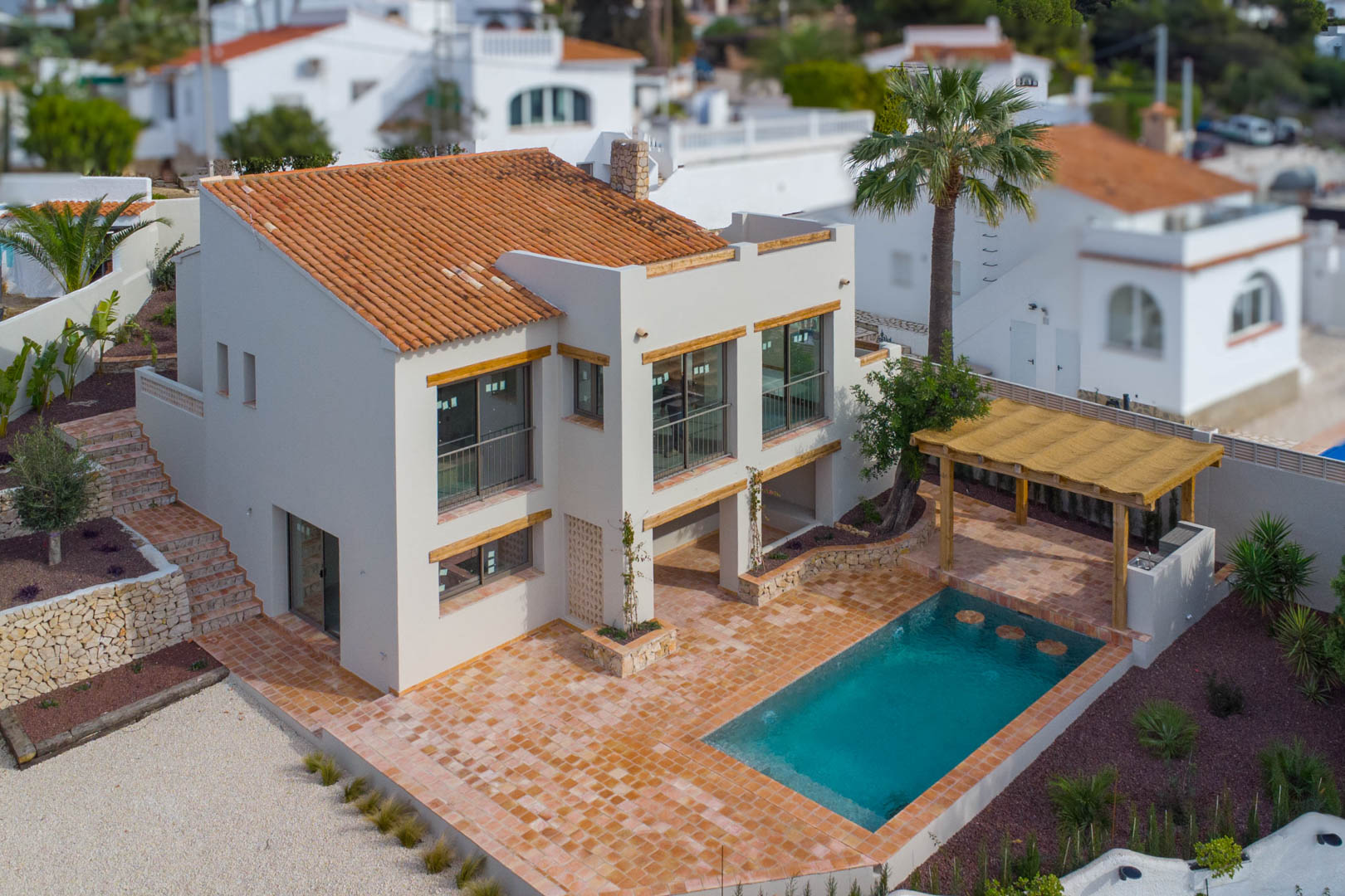 Vue aérienne de la villa avec sa piscine neuve, sa terrasse en terre cuite et sa pergola en bois abritant une cuisine d'été et un espace barbecue.