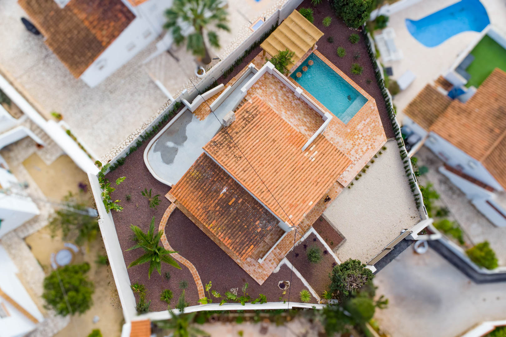 Vue aérienne de la villa révélant l'agencement du terrain, la piscine avec coin salon intégré, les terrasses en terre cuite et le jardin méditerranéen aménagé.