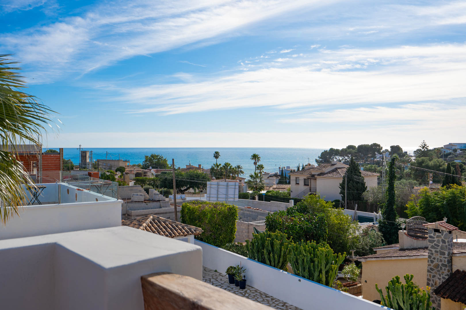 Vue panoramique sur la mer Méditerranée depuis la terrasse sur le toit, avec garde-corps en verre et finitions en bois naturel dominant le littoral.