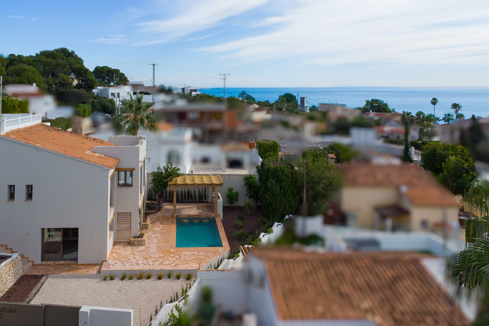 Vue surélevée de la villa avec piscine privée, terrasse en terre cuite et pergola en bois, offrant un panorama sur la mer Méditerranée et le quartier.