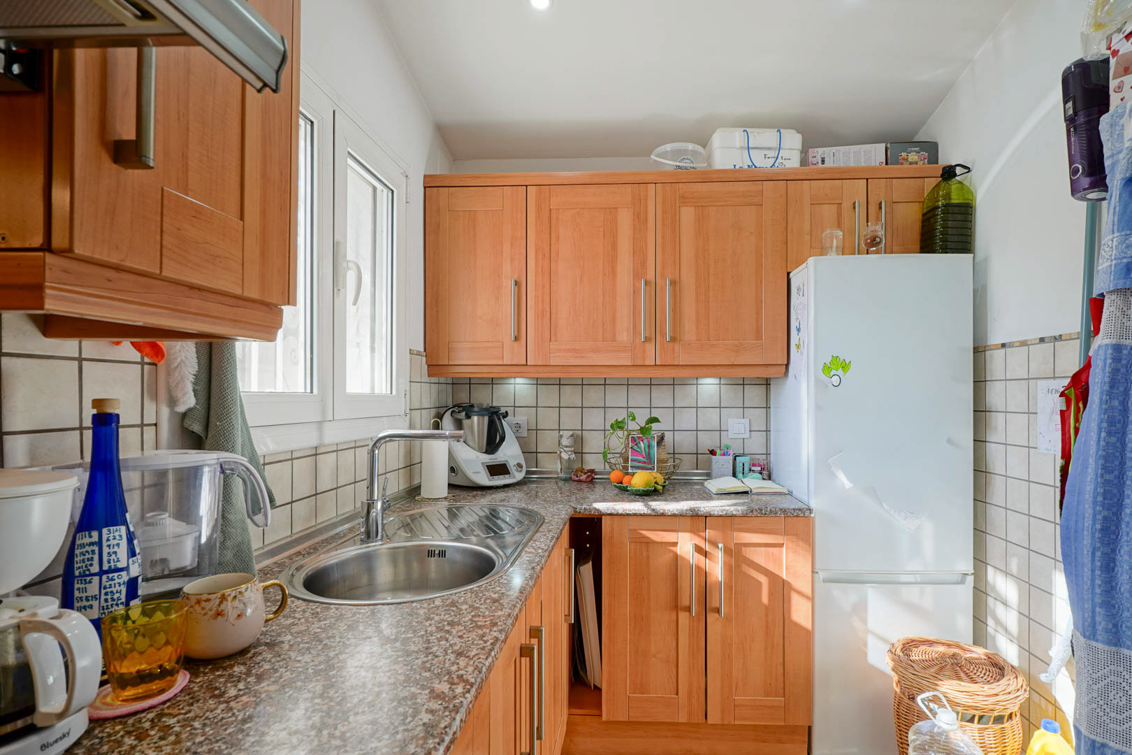 Cuisine indépendante avec des meubles en bois, un plan de travail en granit et un évier en inox. Une fenêtre latérale apporte une lumière naturelle constante.