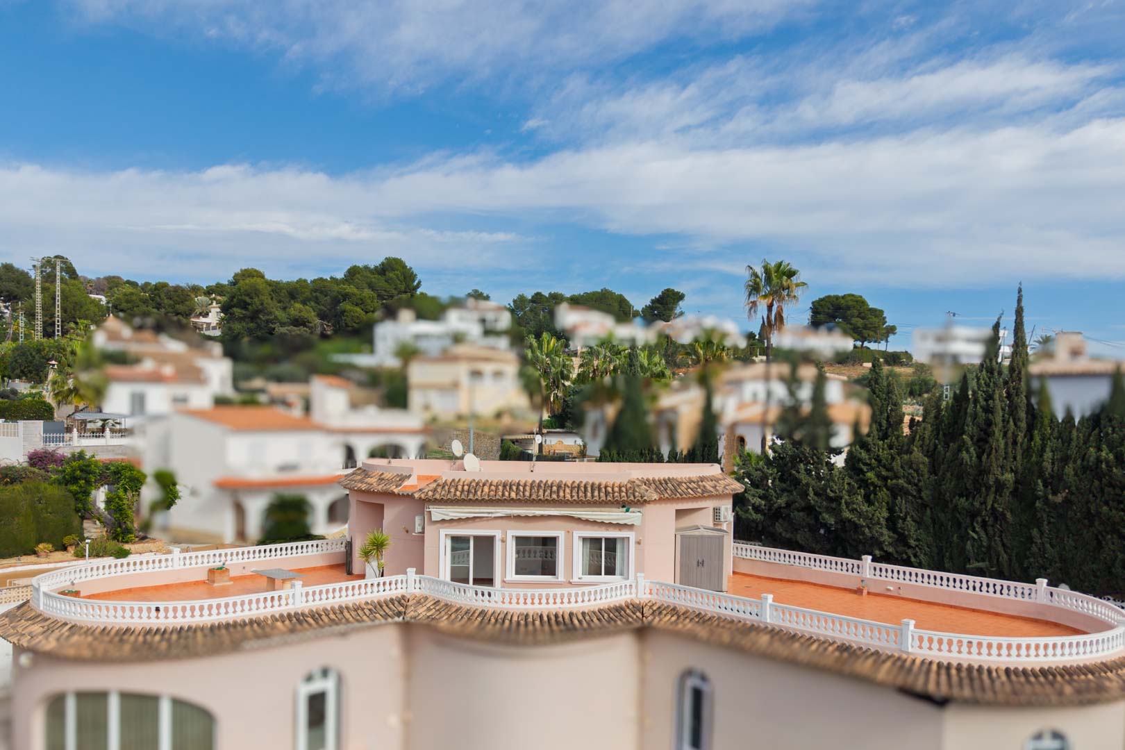 Vue surélevée du penthouse révélant une vaste terrasse périphérique en terre cuite avec balustrades blanches, entourée d'une végétation méditerranéenne.