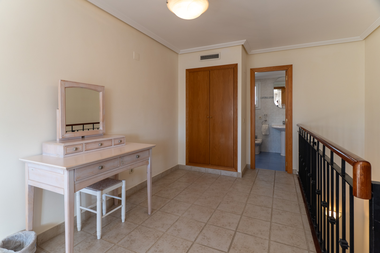 Palier à l'étage avec coiffeuse en bois clair, placard intégré et vue sur une salle de bain attenante avec carrelage bleu.