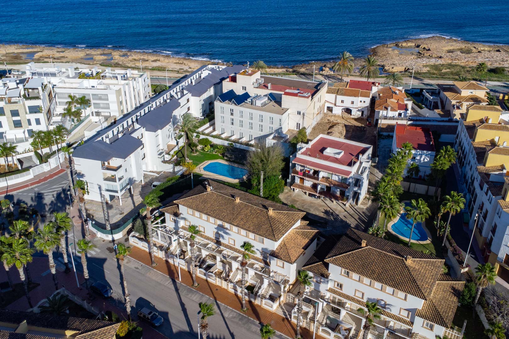 Vue aérienne du complexe résidentiel sur la Calle Génova, soulignant sa proximité avec la mer Méditerranée, ses piscines et ses toits en terre cuite.