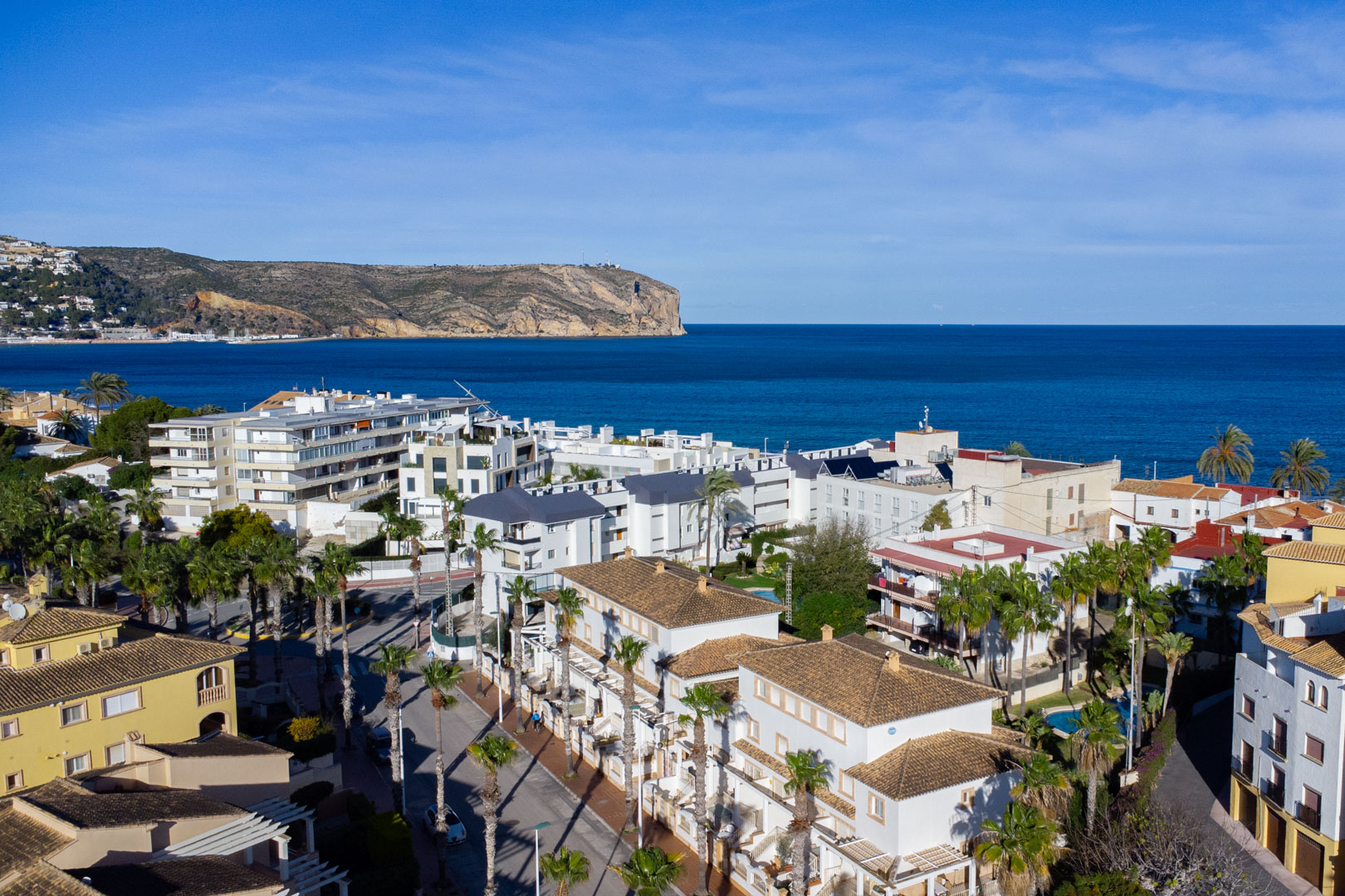 Vue aérienne panoramique de Jávea révélant la proximité de la mer Méditerranée et du Cabo de San Antonio, avec son architecture aux toits de tuiles et ses palmiers.