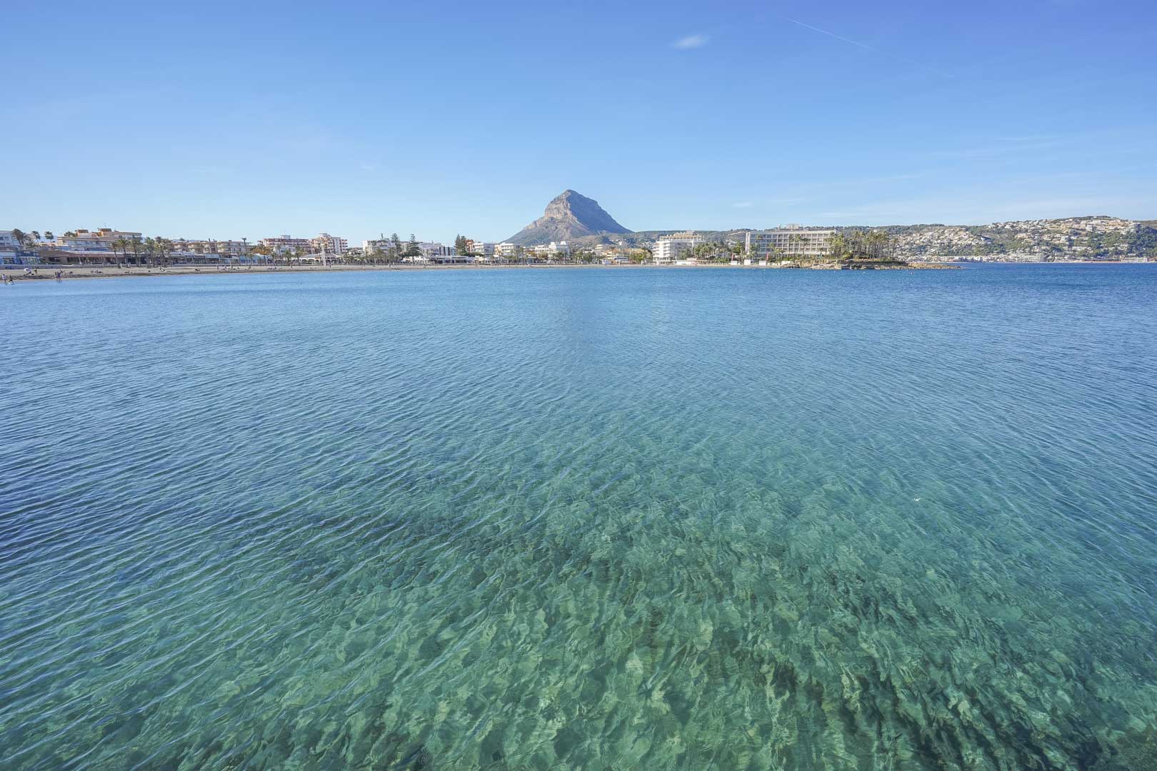 Vue panoramique sur la plage de l'Arenal à Jávea, avec ses eaux cristallines et le mont Montgó en arrière-plan, accessible à pied depuis le logement.