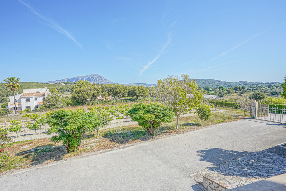 Vue depuis l'allée pavée sur un vignoble privé et le paysage méditerranéen avec le mont Montgó en arrière-plan.