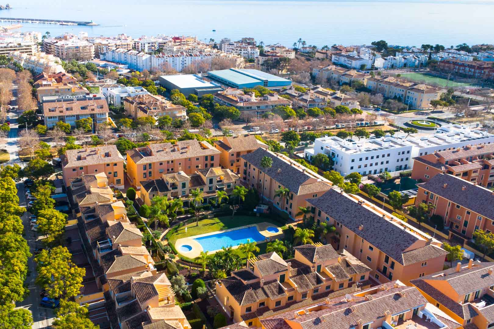 Vue aérienne du complexe Floridamar à Jávea, illustrant la piscine centrale entourée de jardins et la proximité du port et de la mer Méditerranée.