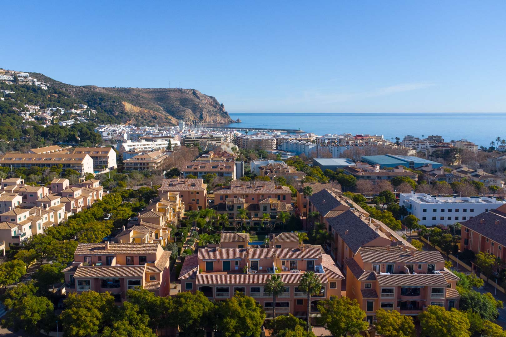 Vue aérienne du complexe Floridamar à Jávea, illustrant l'architecture méditerranéenne et la proximité du port avec le Cabo de San Antonio en arrière-plan.