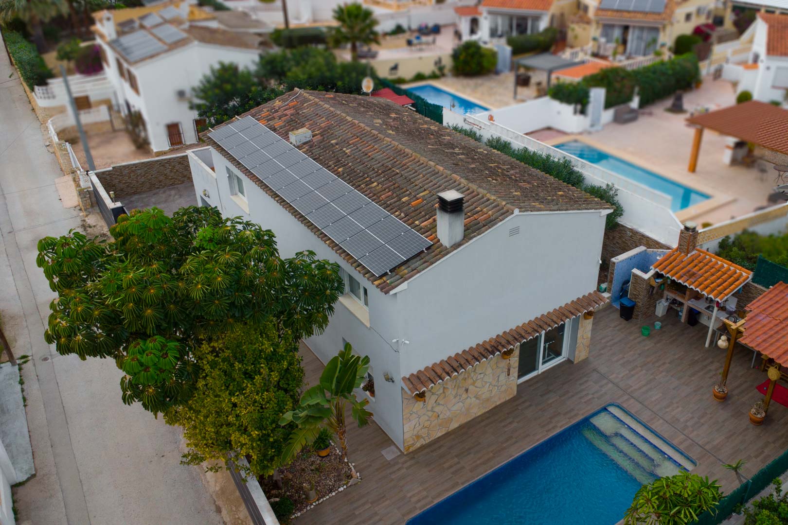 Vue aérienne de la villa illustrant les panneaux solaires sur le toit, la piscine privée et l'espace barbecue extérieur sur une terrasse carrelée.