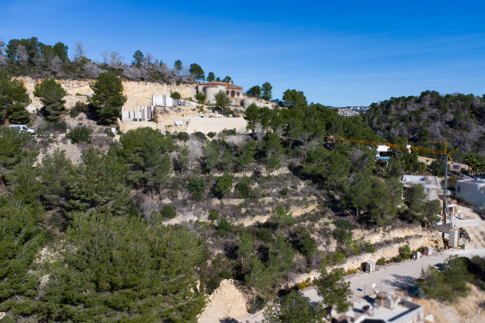 Vue aérienne d'un terrain en pente avec des pins méditerranéens, des murs de soutènement en pierre et des chantiers en cours à Tosalet 5.