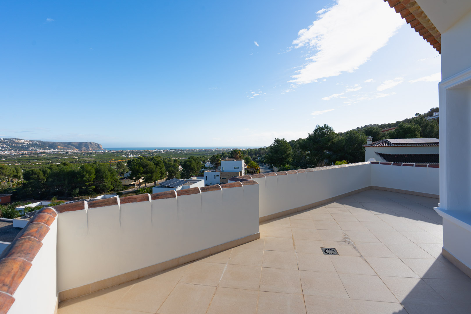 Terrasse supérieure avec carrelage beige et garde-corps en maçonnerie, offrant une vue panoramique sur la mer Méditerranée et la vallée environnante.