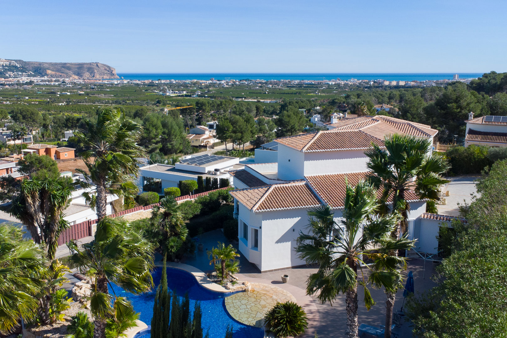 Vue aérienne de la villa blanche avec piscine, entourée de palmiers et offrant une vue panoramique sur la mer Méditerranée.