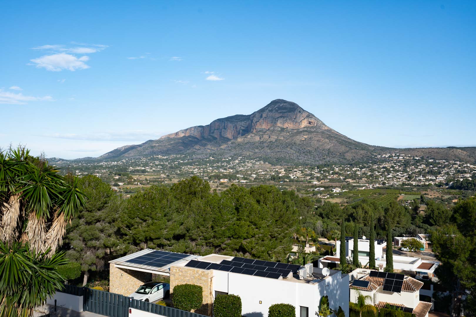 Vue panoramique sur le mont Montgó depuis la propriété, mettant en avant les panneaux solaires en toiture et l'environnement résidentiel boisé de pins.