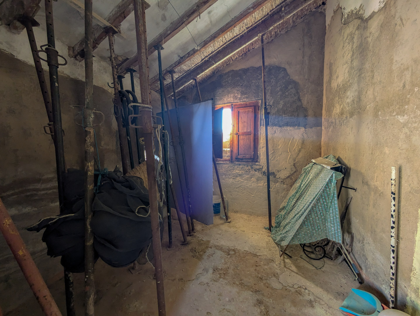 Espace intérieur avec plafonds traditionnels en canisse et poutres en bois, actuellement étayés par des supports métalliques pour sécuriser la structure.