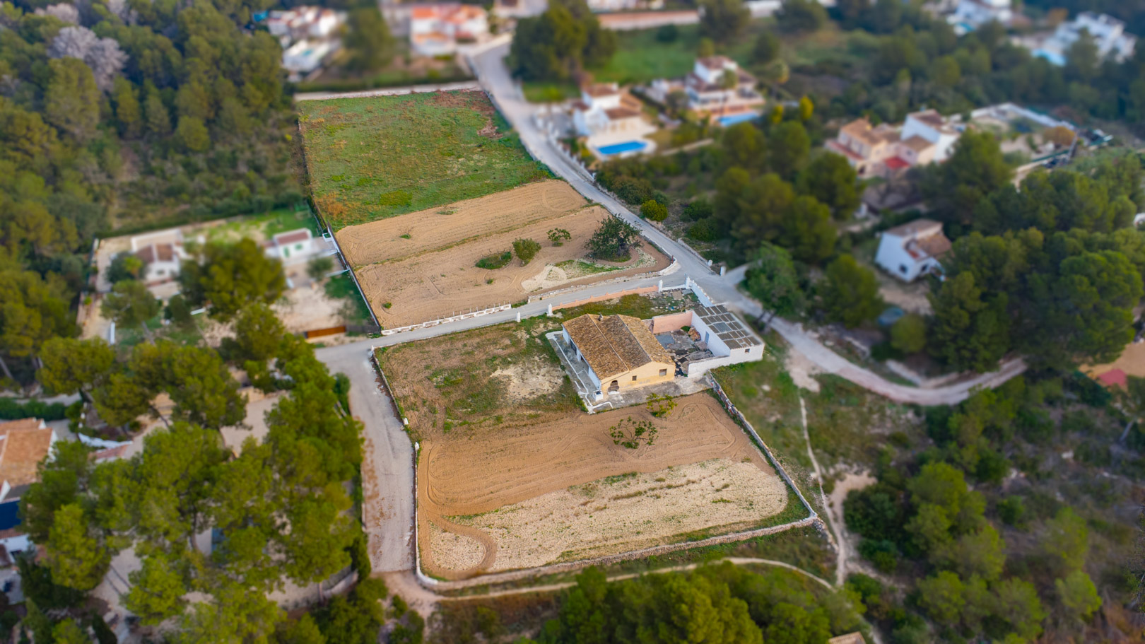 Vue aérienne montrant la finca traditionnelle et l'étendue des parcelles rustiques plates, entourées de végétation méditerranéenne et de pins à Jávea.