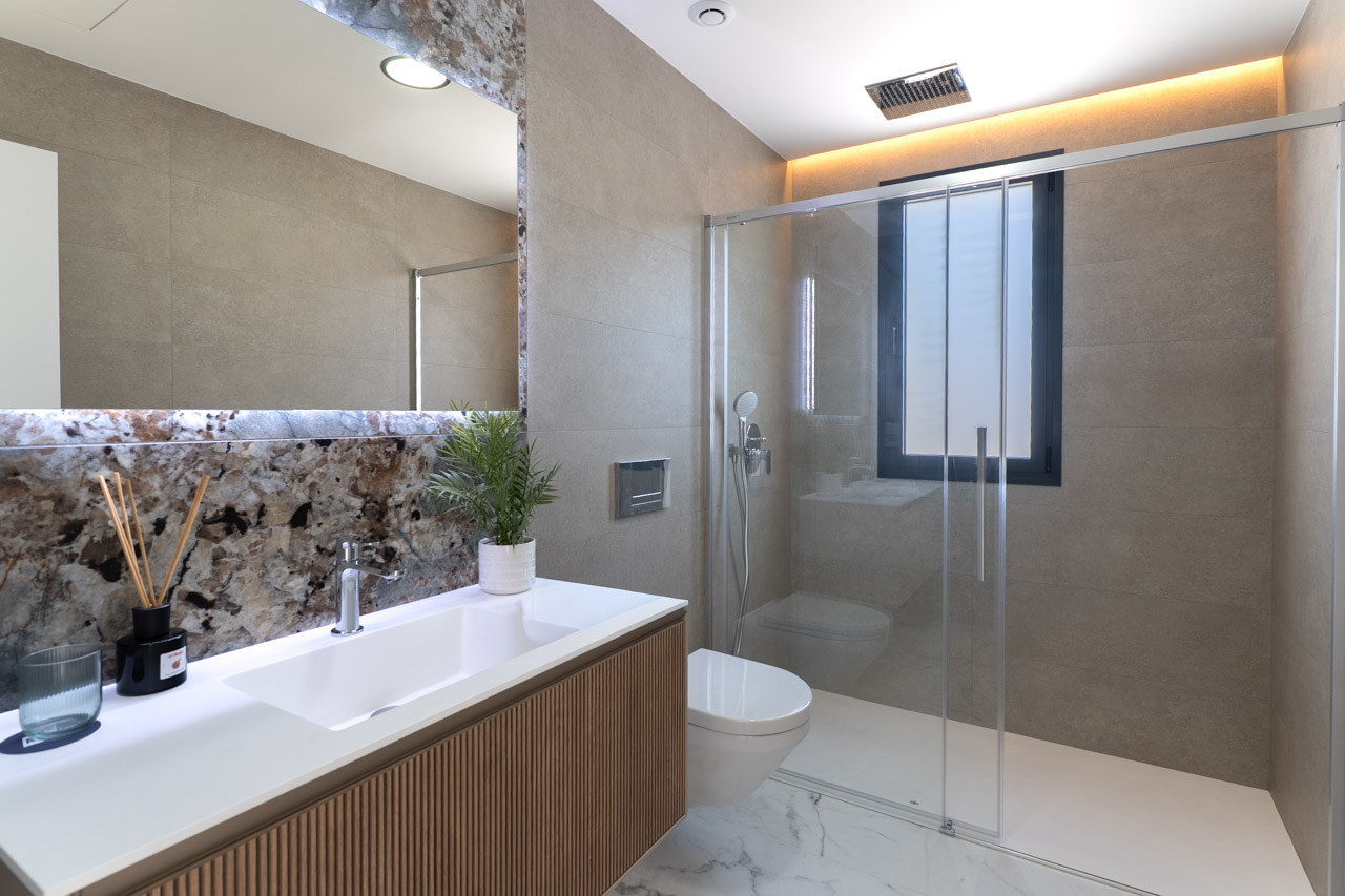 Salle de bain moderne avec meuble en bois à lattes, crédence en marbre et douche à l'italienne dotée d'une paroi vitrée et d'un éclairage LED.