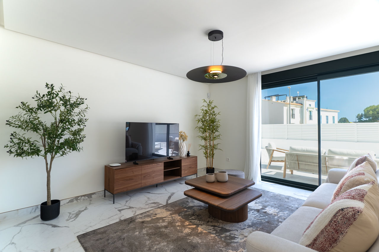 Salon contemporain avec sol en grès cérame effet marbre, mobilier en bois et grandes baies vitrées coulissantes ouvrant sur une terrasse privée.