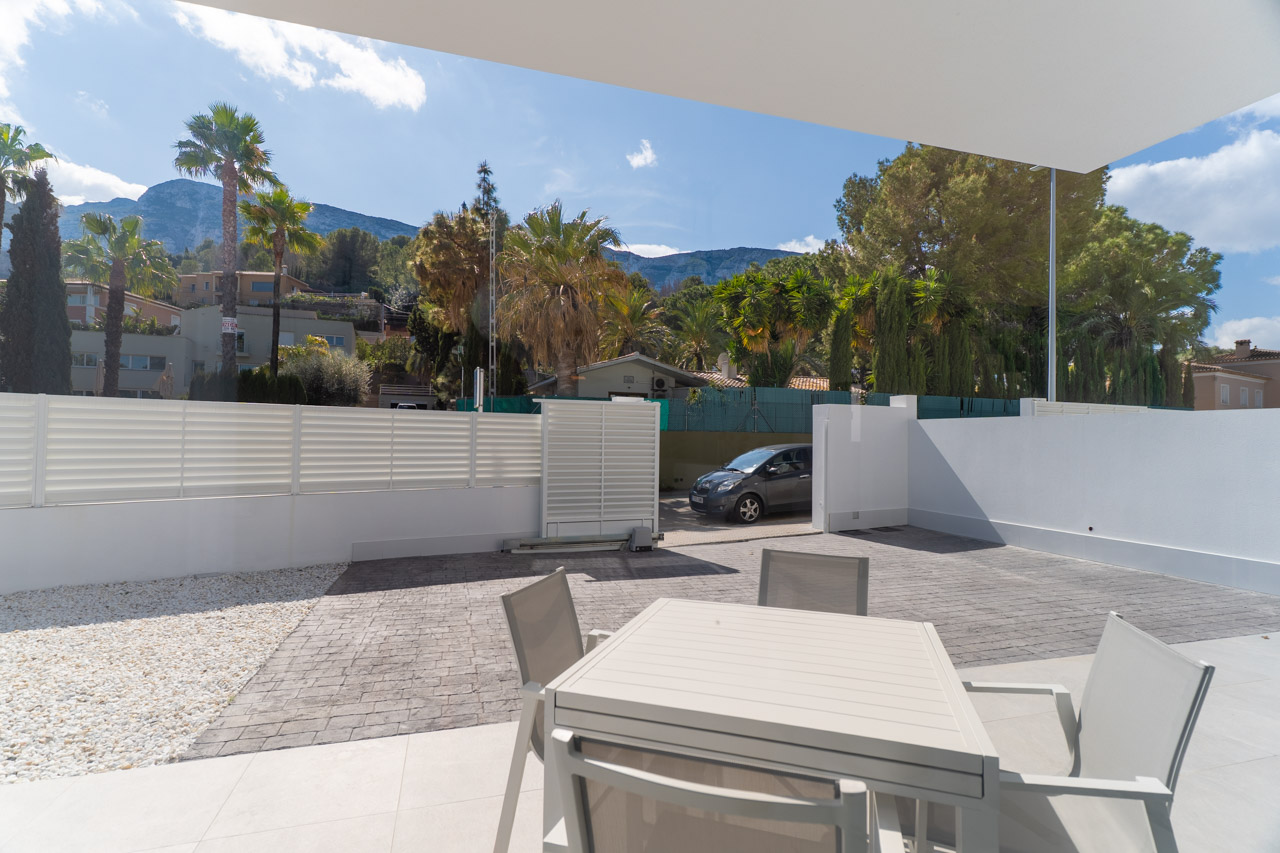 Terrasse extérieure avec espace dînatoire et parking privé. Elle offre une vue dégagée sur le massif du Montgó dans un cadre architectural moderne et épuré.