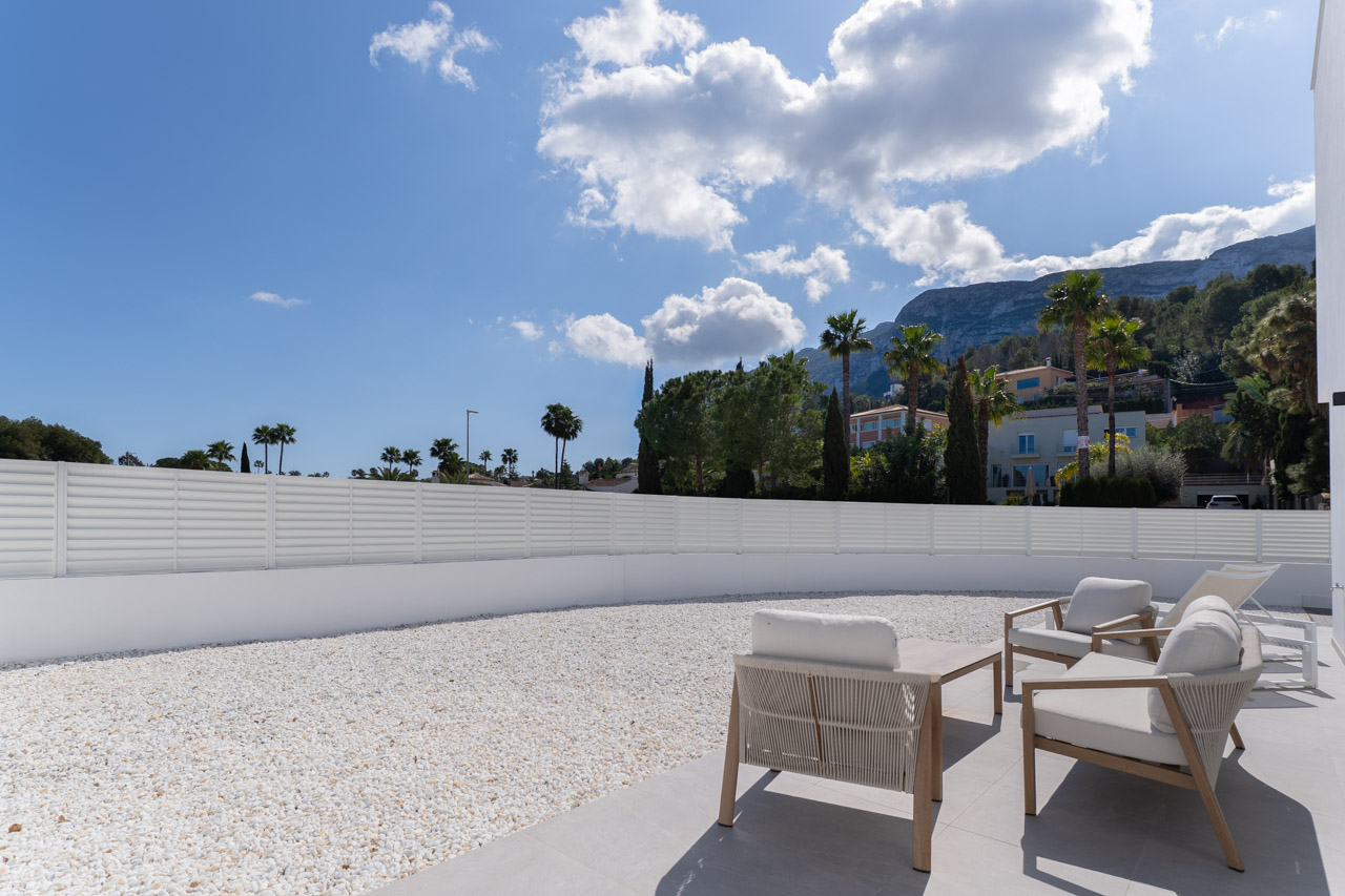Terrasse extérieure avec mobilier de salon, jardin en gravier blanc et vue panoramique sur le massif du Montgó à Dénia.