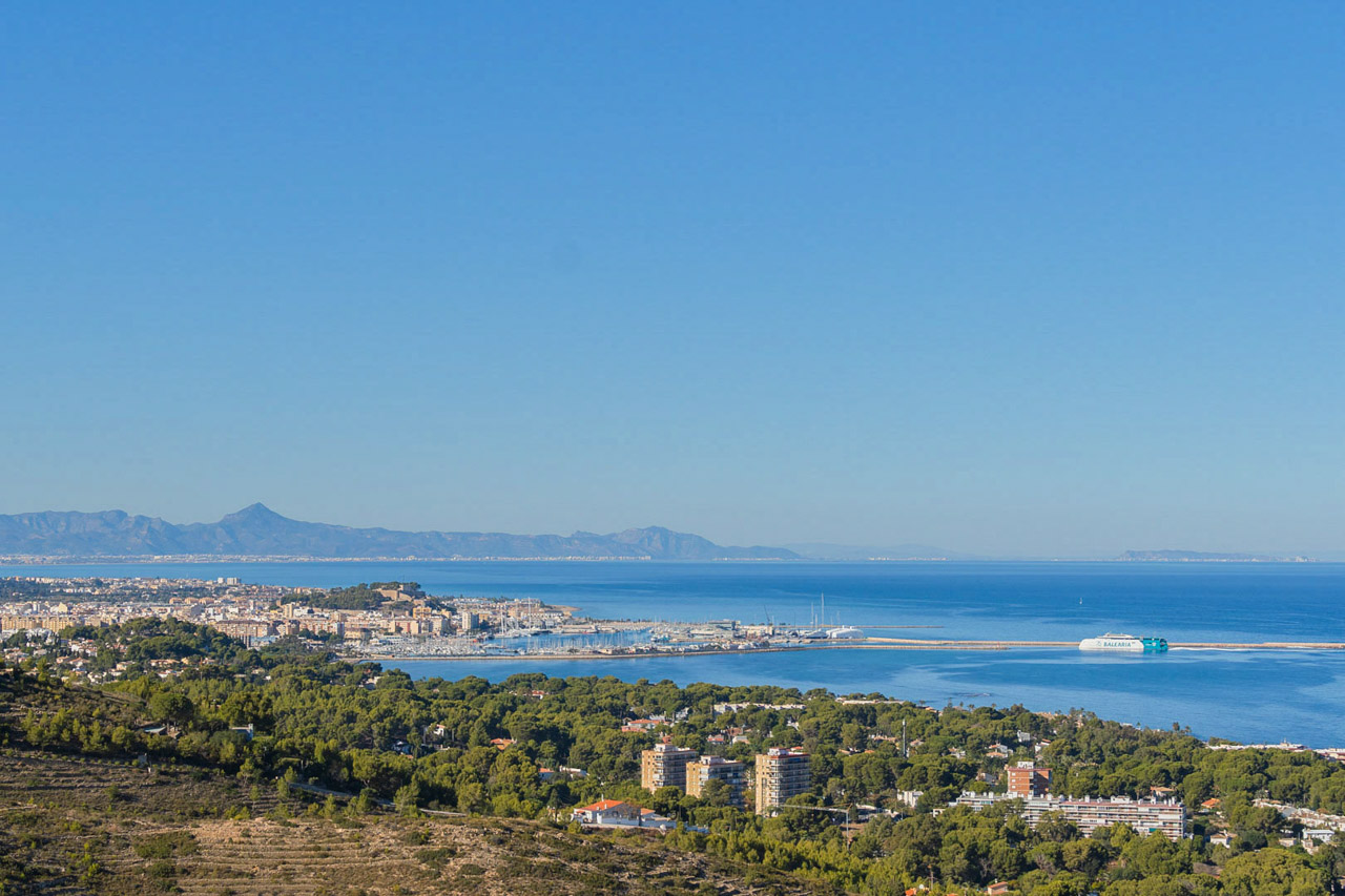 Vue panoramique depuis la propriété sur le port de Dénia et la mer Méditerranée, incluant le château historique et le littoral sous un ciel dégagé.