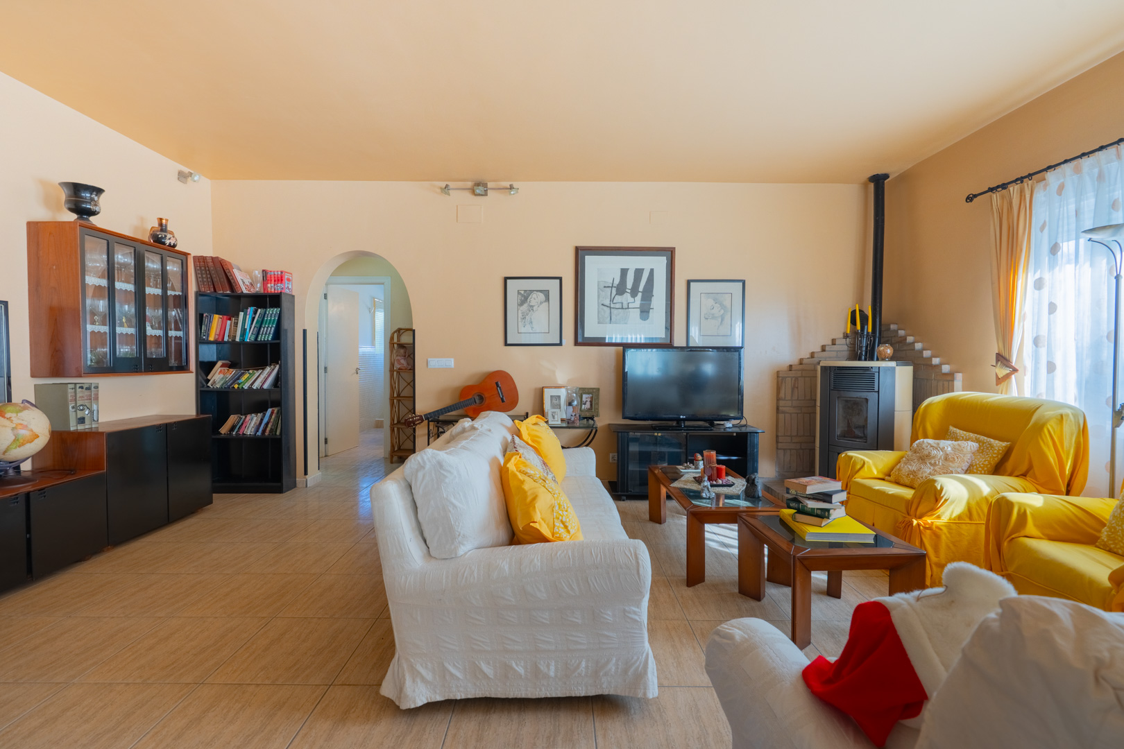 Salon spacieux de style traditionnel avec poêle à bois, sol en grès et une ouverture voûtée menant aux autres pièces de la maison.