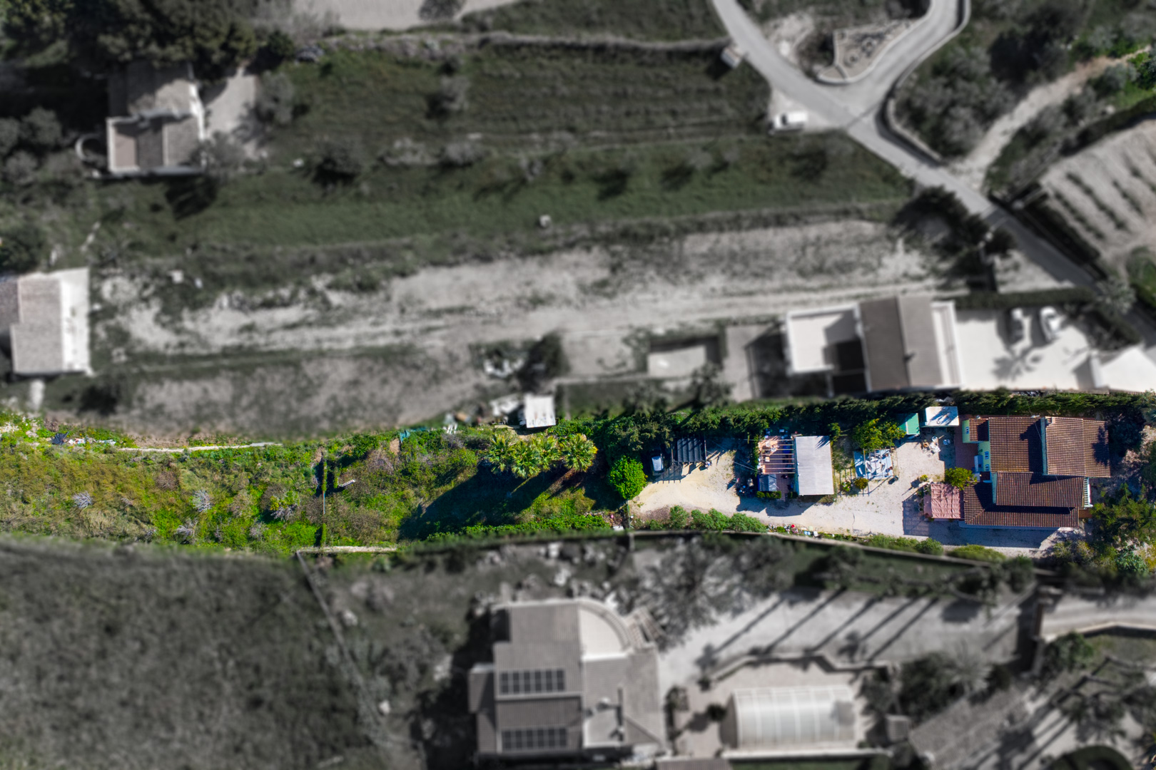 Vue aérienne montrant la disposition de la villa principale, de l'habitation préfabriquée et du terrain rustique en bordure de la vallée de Benitachell.