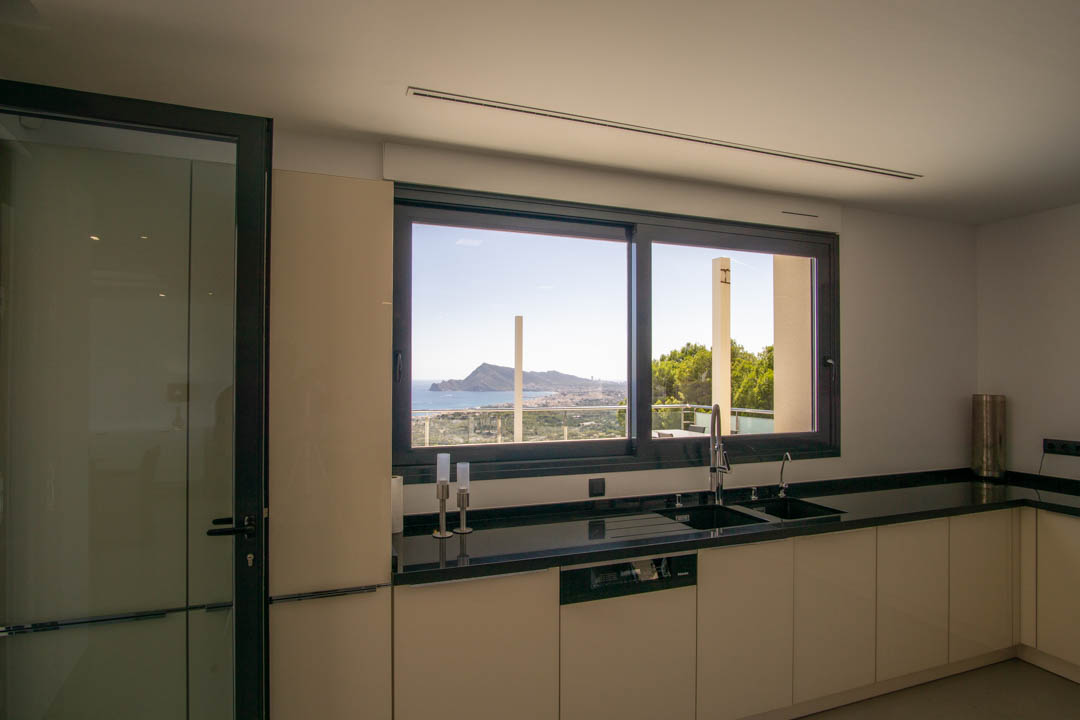 Cuisine moderne avec plan de travail en granit noir et fenêtre panoramique offrant une vue dégagée sur la baie d'Altea et la mer.