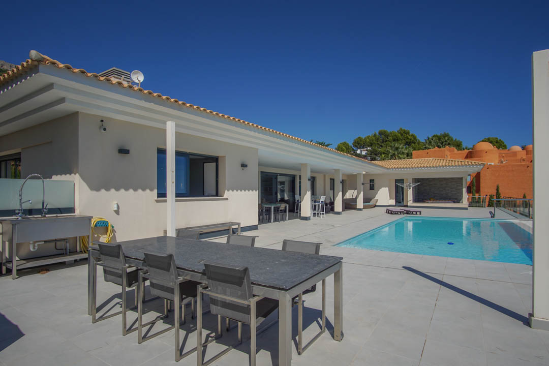 Grande terrasse de 240m2 avec piscine de 10x4m, espace dînatoire extérieur et cuisine d'été équipée d'un évier professionnel en acier inoxydable.