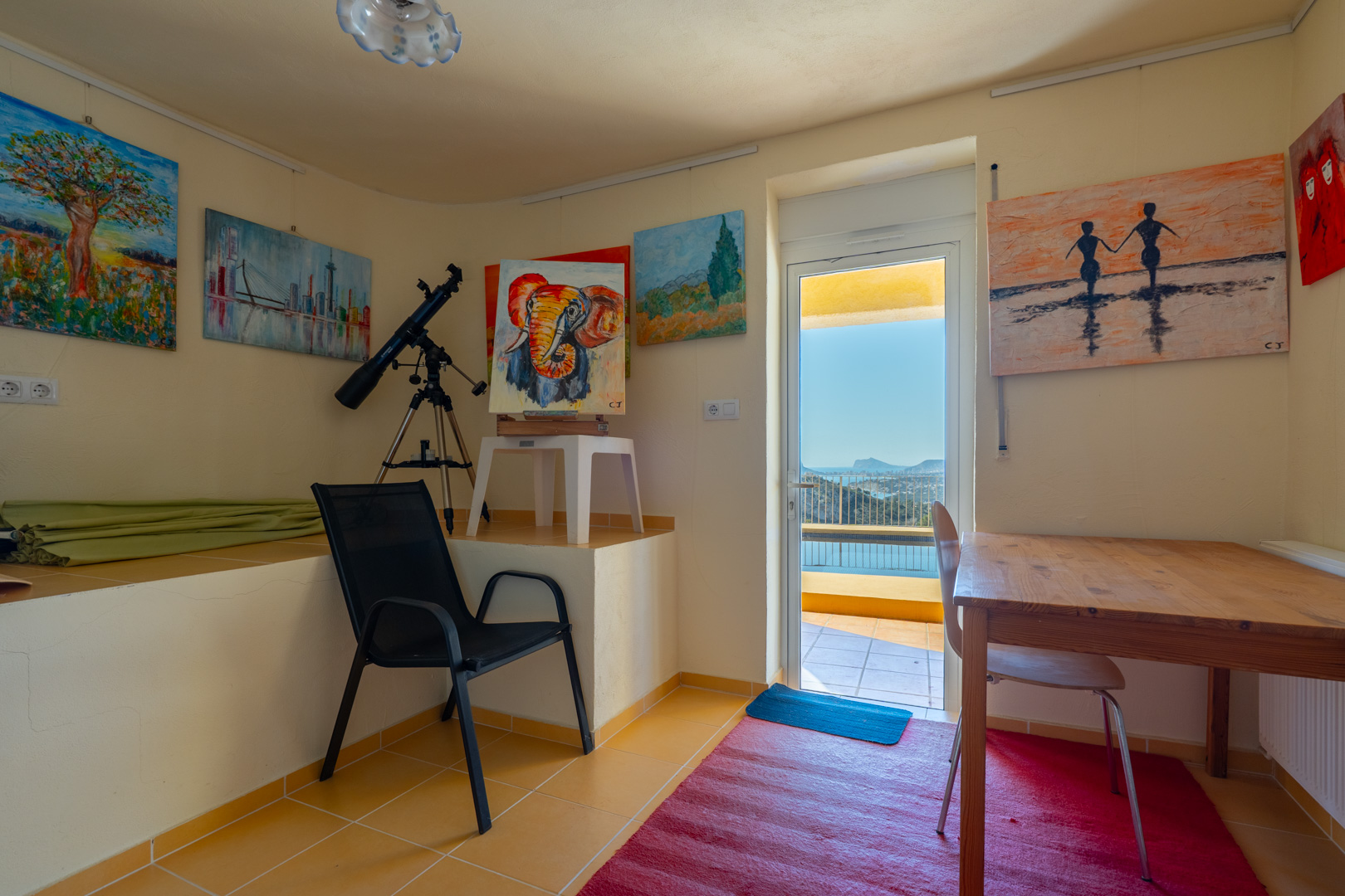 Bureau lumineux faisant office d'atelier d'artiste, équipé d'un télescope et offrant un accès direct à la terrasse avec vue sur la côte.