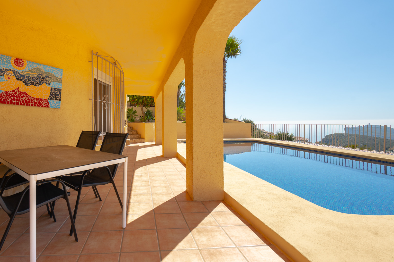 Terrasse couverte avec arches traditionnelles, coin repas extérieur et piscine privée offrant une vue panoramique sur la mer et le Cap d'Or.