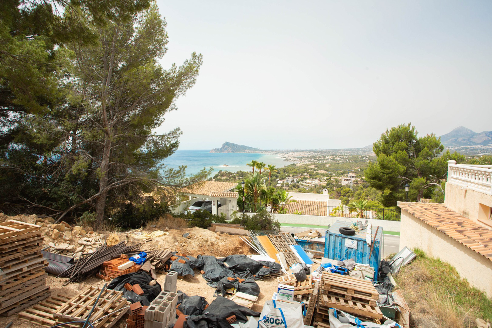Vue surélevée depuis le terrain d'Altea Hills, montrant des matériaux de construction et un panorama sur la mer Méditerranée et la côte d'Altea.
