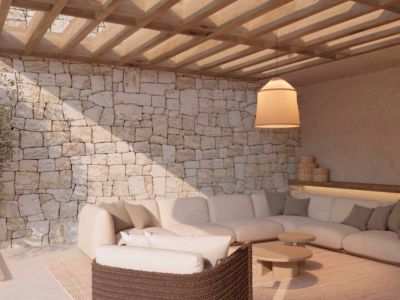 Espace salon extérieur avec mur en pierre naturelle, pergola en bois et grand canapé d'angle. L'éclairage suspendu et le mobilier moderne définissent l'ambiance.