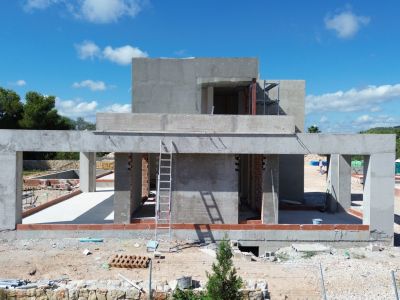 Carcasse en béton de la villa en début de construction, dévoilant l'ossature et les ouvertures de fenêtres.