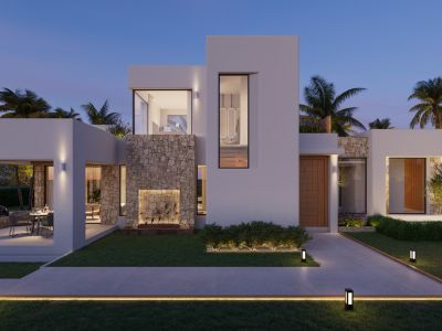 Extérieur de villa contemporaine au crépuscule, avec façades blanches, parements en pierre naturelle et salle à manger extérieure couverte éclairée. Allées et jardin sont illuminés.