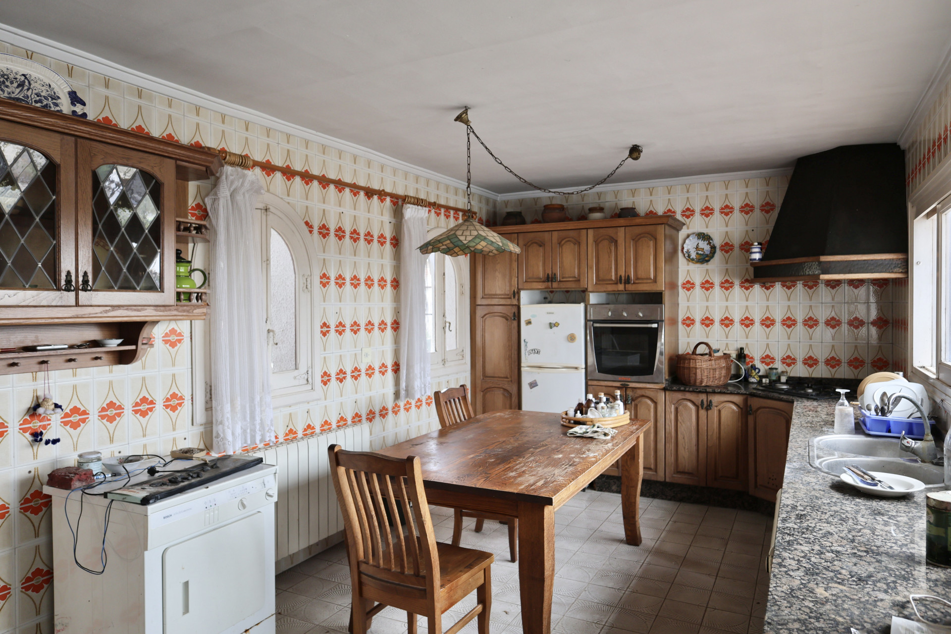 Cuisine avec carrelage à motifs et mobilier en bois, à rénover.