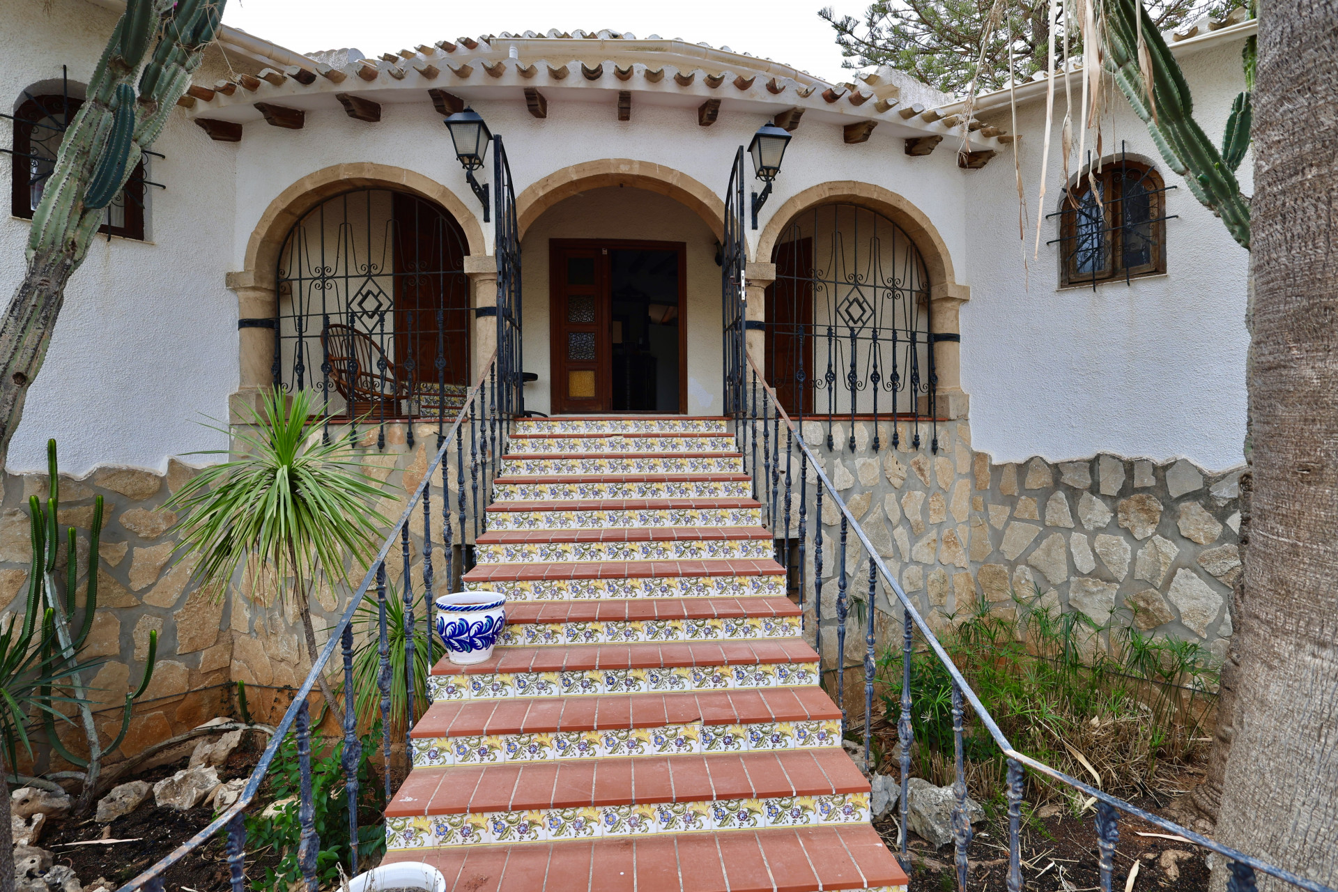 Entrée principale de la villa avec marches en terre cuite et détails floraux.