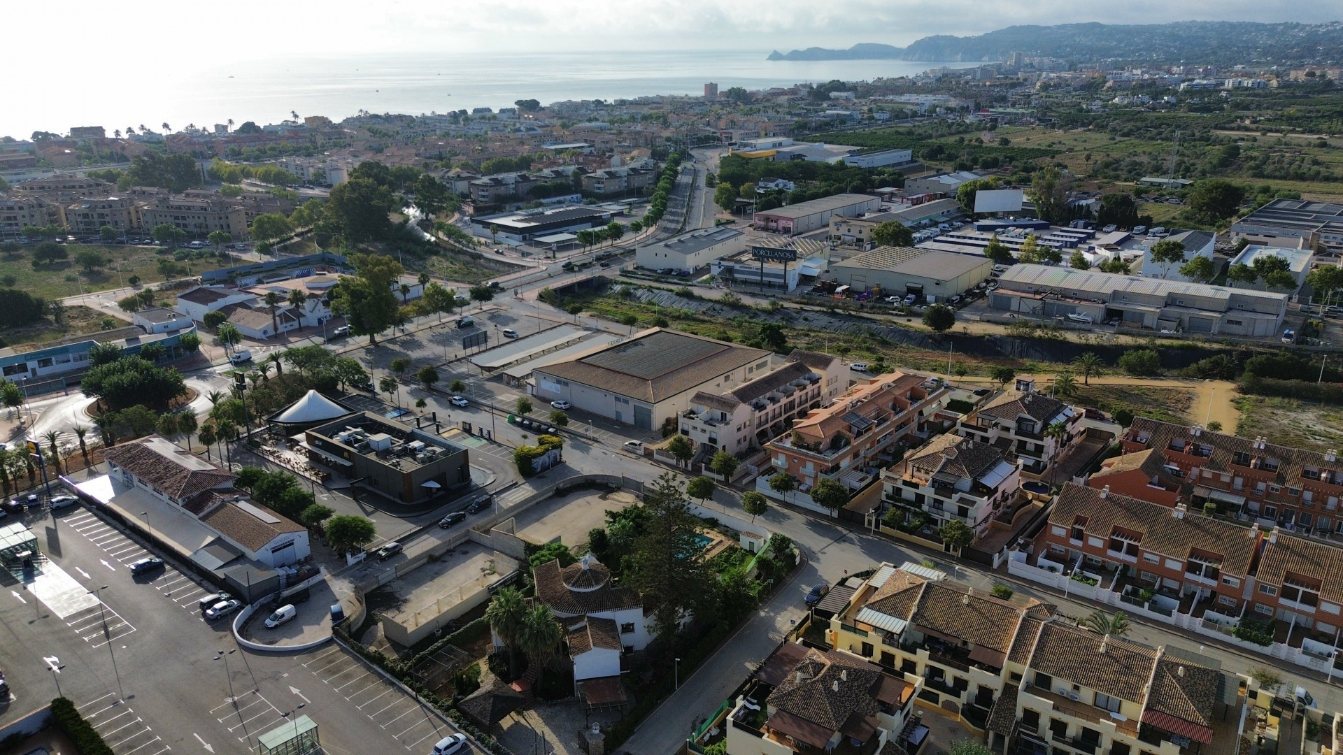 Vue aérienne de Jávea avec des bâtiments résidentiels, commerciaux et la mer Méditerranée en arrière-plan.