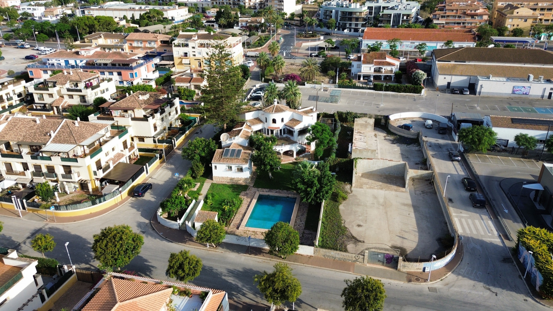 Vue aérienne de la villa avec piscine bleue entourée de jardins et de bâtiments urbains à Jávea.