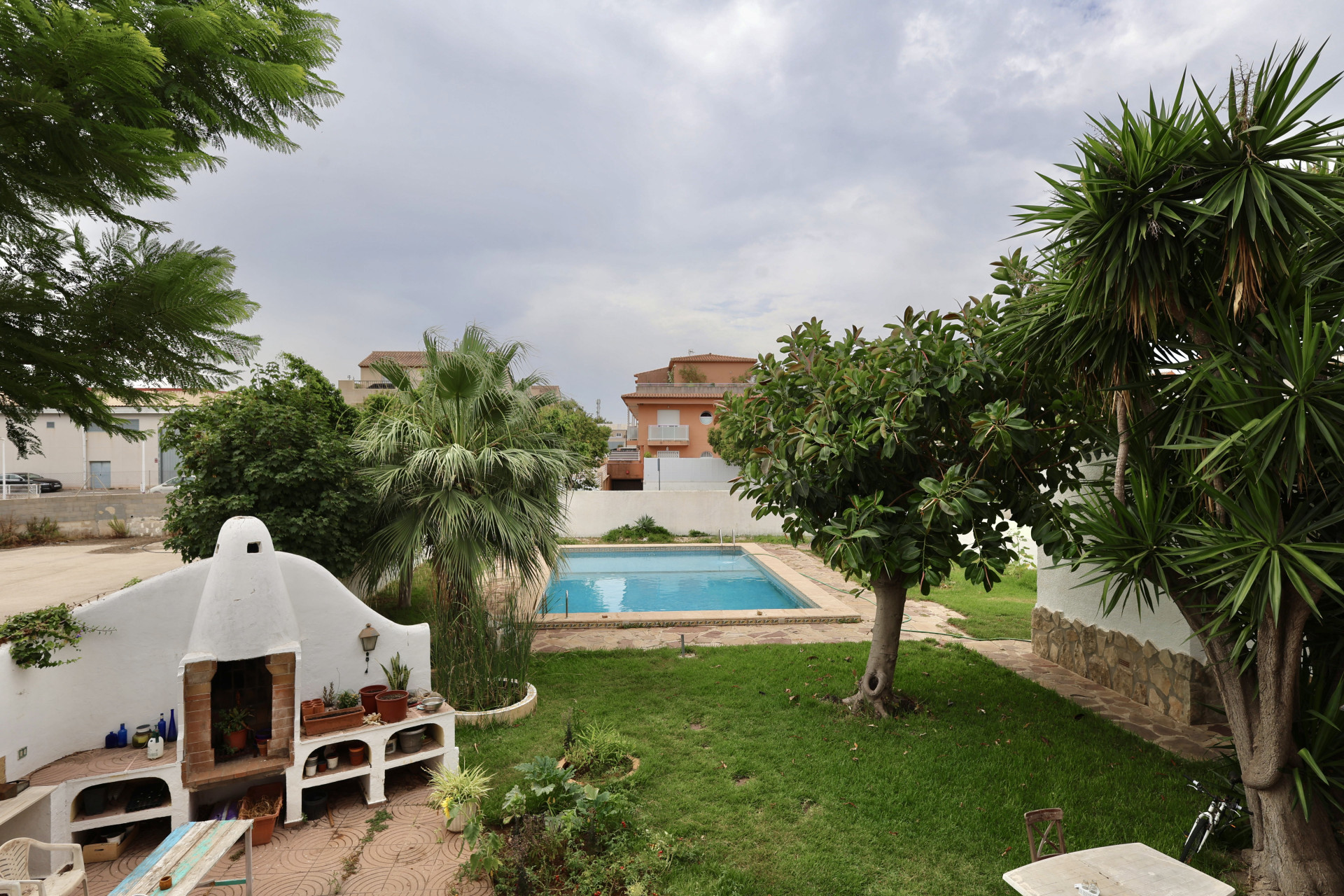 Vue du jardin avec piscine, barbecue en brique et végétation luxuriante à Jávea.